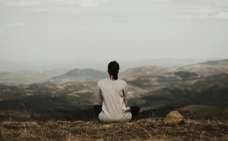 Pige sidder og kigger ud på bjerge