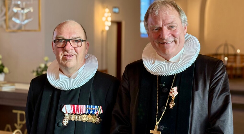 Biskop Henrik Stubkjær og provst Ole Rasmussen, begge iført sorte præstekjoler med hvide pibekraver, stående i en kirkelig sammenhæng.